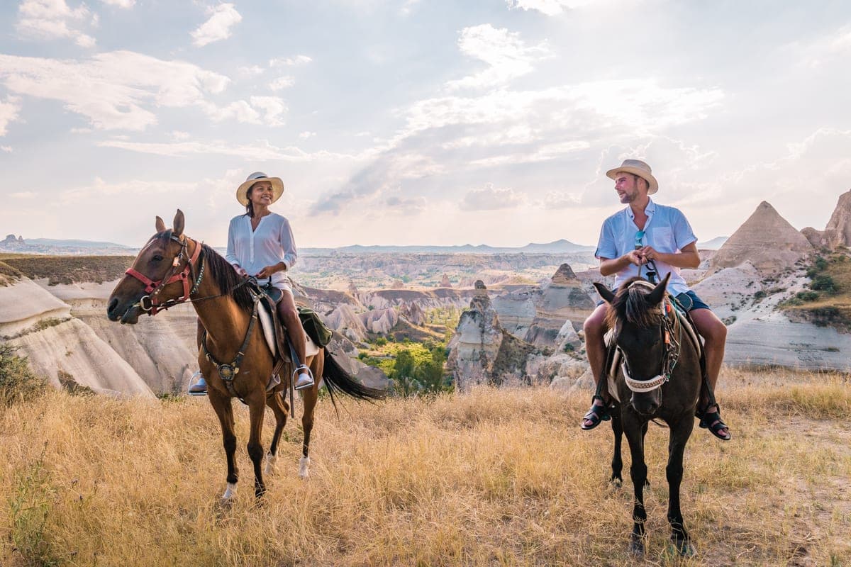Two riders on Anatolian horses on a ridge above the Cappadocia valleys