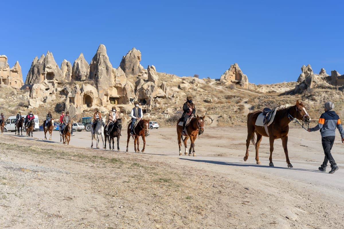 A group ride in single file returning past cave dwellings